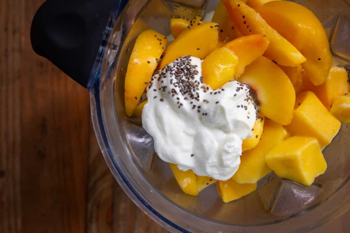 Peach mango smoothie ingredients in a blender