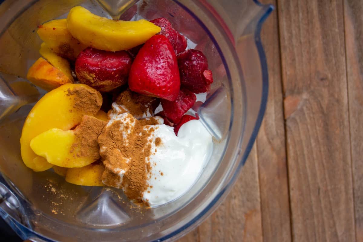 Frozen peach and strawberries in a blender